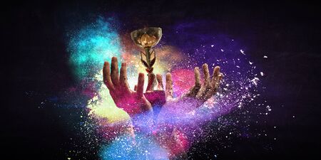 Hand holding up a gold trophy cup against dark backgroundの写真素材