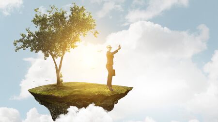 Businesswoman standing against landscape and making selfie. Mixed mediaの写真素材