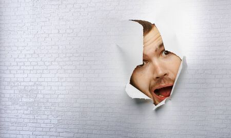 Male face through the hole in paper