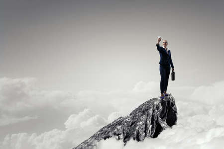 Businesswoman standing against landscape and making selfieの写真素材