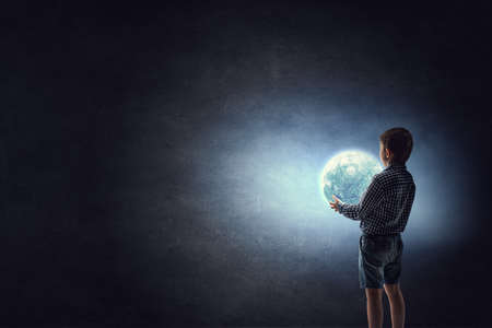 Boy holding moon at nightの写真素材