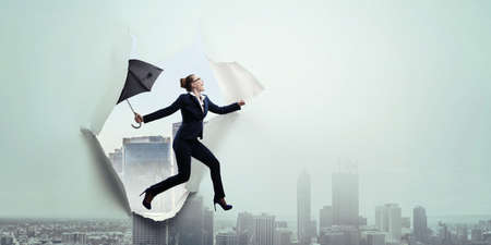 Young businesswoman walking with umbrellaの写真素材