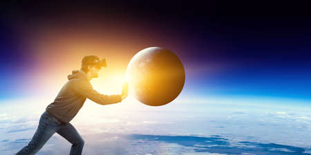 Young businessman in VR glasses rolling the Earthの写真素材