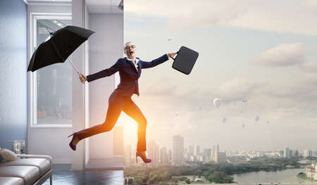 Young businesswoman walking with umbrellaの写真素材