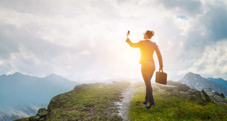 Businesswoman standing against landscape and making selfieの写真素材