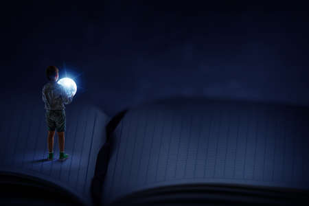 Boy holding moon at nightの写真素材