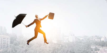 Young businesswoman walking with umbrellaの写真素材