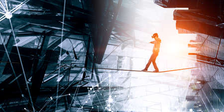 Man wearing virtual reality goggles and balancing on ropeの写真素材