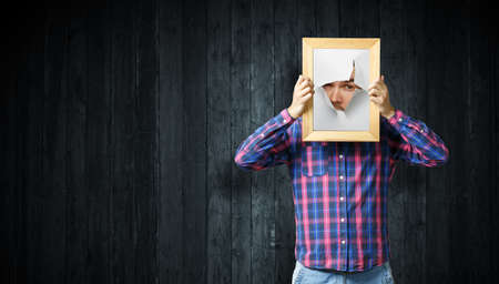 Male face through the hole in paperの写真素材