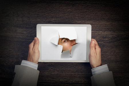 Male face through the hole in paper