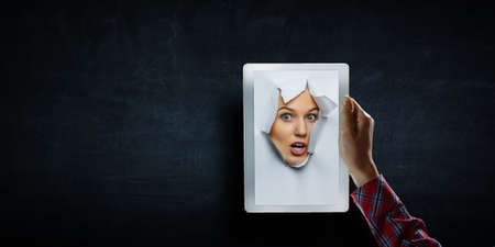 Female face through the hole in paperの写真素材