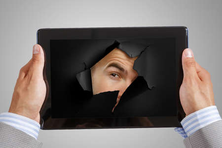 Male face through the hole in paperの写真素材