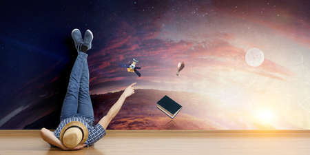 Young man lying on the floor with legs raised up on the wall. Mixed mediaの写真素材