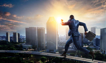 Running black businessman with briefcaseの写真素材