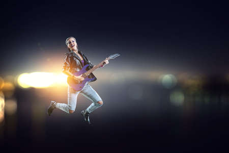 Young and beautiful rock girl playing the electric guitar