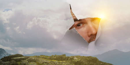 Male face through the hole in paperの写真素材