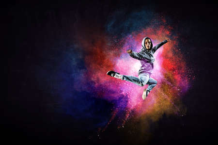 Modern female dancer jumping in hoodie with colourful splashes background. Mixed mediaの写真素材
