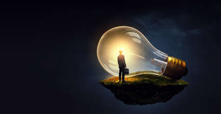 Huge light bulb glowing in the darkness .