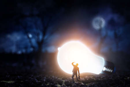 Huge light bulb glowing in the darknessの写真素材