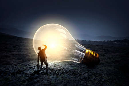 Huge light bulb glowing in the darknessの写真素材