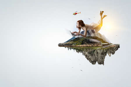 Young woman levitates while reading a bookの写真素材