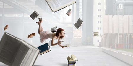 Young woman levitates while reading a bookの写真素材