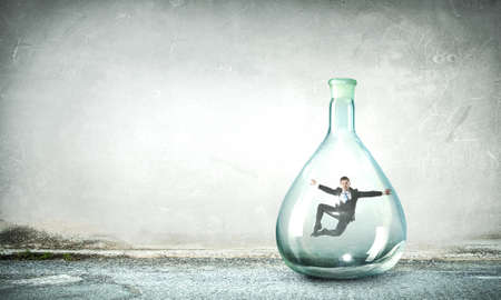 Young businessman dancing inside glass bottleの写真素材