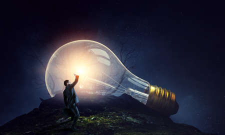 Huge light bulb glowing in the darknessの写真素材