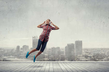 Woman wearing headphones jumping . Mixed mediaの写真素材