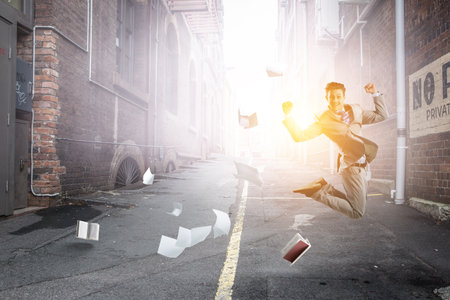 Portrait of energetic businessman jumping in open airの写真素材