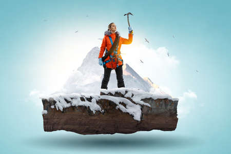 Mountaineer reaches the top of a snowy mountainの写真素材