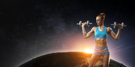 Young beautiful girl doing exercise against dark backgroundの写真素材