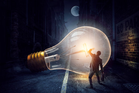 Huge light bulb glowing in the darknessの写真素材