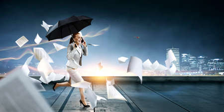 Businesswoman running with umbrella . Mixed mediaの写真素材