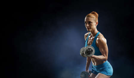 Young beautiful girl doing exercise against dark backgroundの写真素材