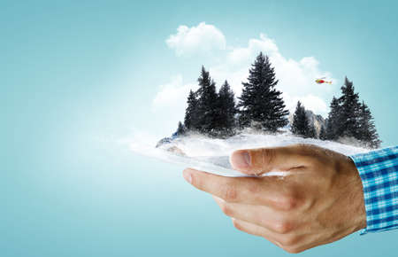 Smartphone in the hands and the mountains in winterの写真素材