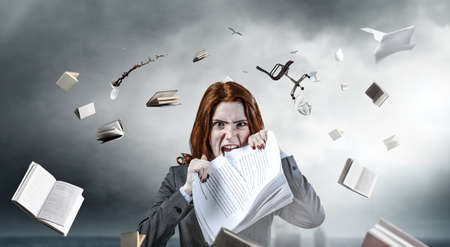 Young stressed woman ripping documents with frustrated facial expression.の写真素材