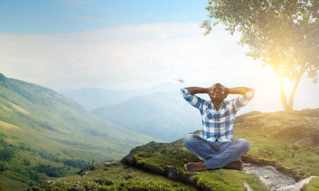 Young black man sitting and meditating . Mixed mediaの写真素材