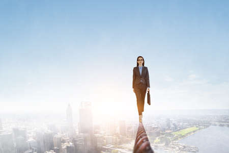 Image of businesswoman balancing on rope. Risk concept . Mixed mediaの写真素材