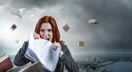Young stressed woman ripping documents with frustrated facial expression.の写真素材