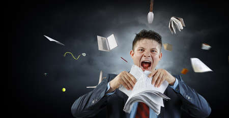 Young stressed man ripping documents with frustrated facial expression.