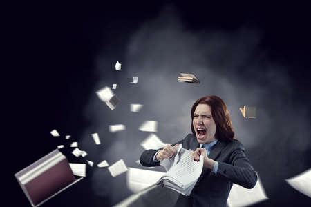 Young stressed woman ripping documents with frustrated facial expression.の写真素材