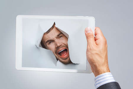 Male face through the hole in paper