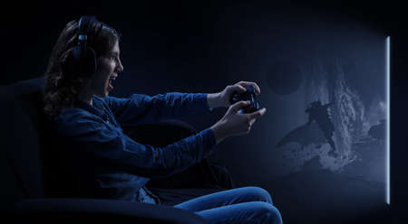 A woman in headphones with a controller set aside in her handsの写真素材