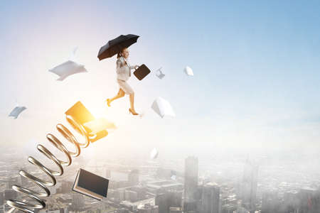 Businesswoman running with umbrella . Mixed mediaの写真素材