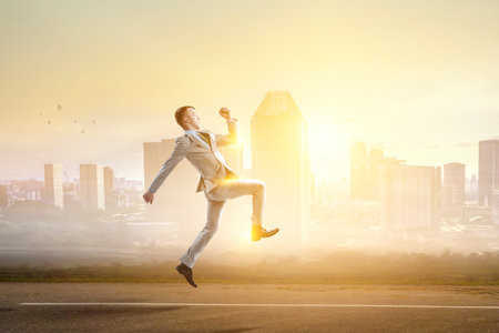 Portrait of energetic businessman jumping in open airの写真素材