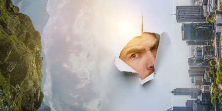 Male face through the hole in paperの写真素材