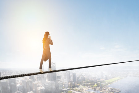 Image of businesswoman balancing on rope. Risk conceptの写真素材