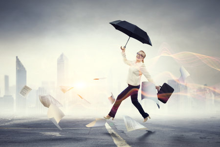 Businesswoman running with umbrella. Mixed media contentの写真素材