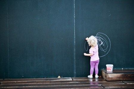 little girl writing on big blackboardの写真素材